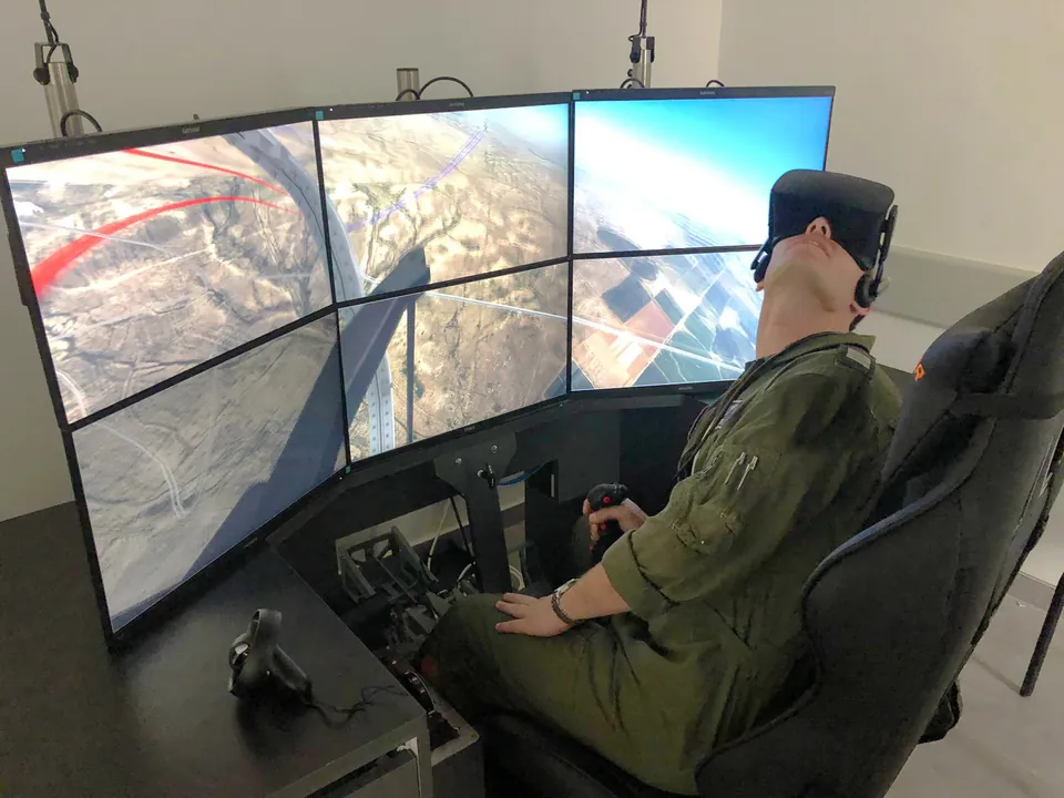 Trainee in a VR headset at a multi-screen training station